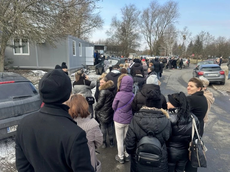 Kolejka osób stojących przed budynkiem TOZ