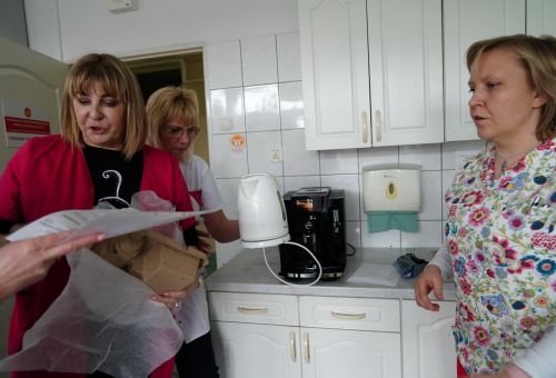 Trzy kobiety w kuchni stoją przy czajniku elektrycznym i ekspresie do kawy